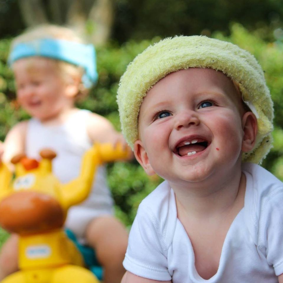 Bumpa Banz baby smiling and wearing yellow bumpa banz head protection.